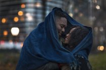 Romántico feliz pareja disfrutando de la ciudad durante las vacaciones de invierno envueltos juntos bajo bufanda - foto de stock