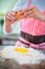 Reife Frau knackt Ei auf Mehl, Mittelteil — Stockfoto