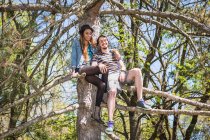 Couple sitting in tree, portrait — Stock Photo