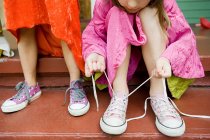 Two girls, one tying up shoelace — Stock Photo