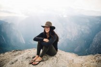 Portrait de jeune femme assise au sommet de la montagne, surplombant le parc national de Yosemite, Californie, États-Unis — Photo de stock