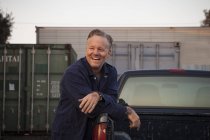 Uomo appoggiato al camion e sorridente — Foto stock