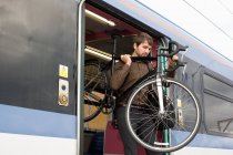 Hombre con bicicleta en tren - foto de stock