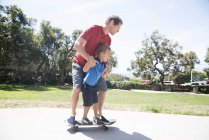 Pai e filho no parque praticando skate — Fotografia de Stock
