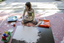 Menina na pintura garagem com rolo de pintura e escova — Fotografia de Stock