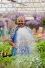 Зрілий садівник поливає рослини в садовому центрі, портрет — стокове фото