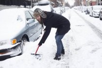 Молодой человек убирает снег с дороги лопатой — стоковое фото