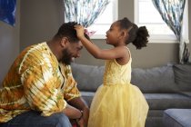 Mädchen im Prinzessinnenkostüm legt Vater im Wohnzimmer Diadem an — Stockfoto
