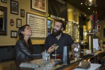 Young couple at table laughing in public house — Stock Photo