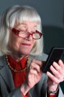 Старша жінка використовує смартфон — стокове фото