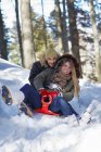 Couple tobogganing in snow — Stock Photo