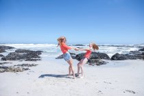 Cape Town, South Africa, two young girls swinging one another at the beach — Stock Photo