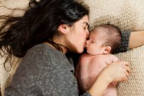 Mother kissing newborn infant on bed — Stock Photo