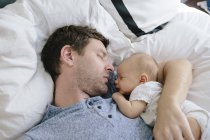 Père et bébé garçon dormant sur le lit — Photo de stock