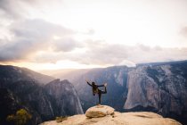 Young woman standing in yoga pose, at top of mountain overlooking Yosemite National Park, California, USA — Stock Photo