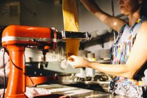Frau macht Teig mit Nudelmaschine platt — Stockfoto