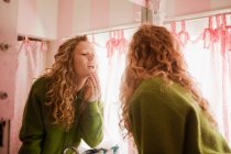 Дівчина-підліток перевіряє шкіру у дзеркалі ванної кімнати — стокове фото