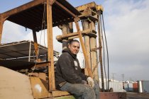 Homme sur chantier assis sur des machines lourdes — Photo de stock