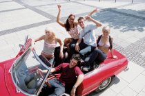 Group of young friends sitting on car — Stock Photo