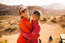 Friends hugging and looking at camera, Buttermilk Boulders, Bishop, California, USA — Stock Photo