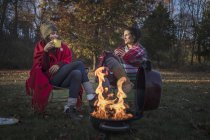 Zwei Freundinnen trinken heißen Tee am Lagerfeuer — Stockfoto