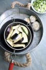 Sieve with sliced aubergines, green chilies and garlic bulbs — Stock Photo