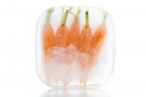 Frozen carrots in ice block — Stock Photo