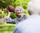 Senior woman throwing football to partner — Stock Photo