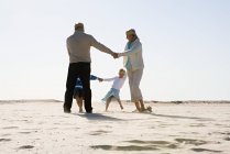 Бабусі і дідусі танцюють з онуками на пляжі — стокове фото