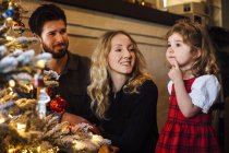 Criança feminina com os pais olhando para a árvore de Natal — Fotografia de Stock