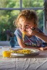 Fille manger assiette de pâtes à la table — Photo de stock