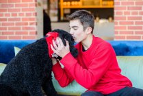 Ragazzo adolescente che gioca con cane da compagnia sul divano — Foto stock