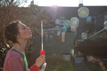 Молодая женщина выдувает пузыри на улице — стоковое фото