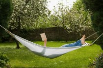 Woman reading book while lying in hammock — Stock Photo