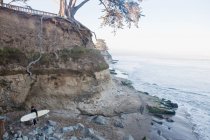 Самотній серфер на кам'янистому пляжі — стокове фото