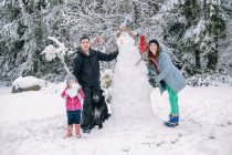 Retrato de familia joven, muñeco de nieve de construcción - foto de stock
