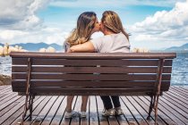 Vue arrière de la mère et de la fille sur le banc du parc s'embrassant — Photo de stock