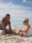 Mother and daughter playing in sand — Stock Photo