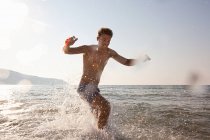 Jeune homme éclaboussant dans la mer — Photo de stock