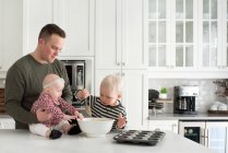 Батько і діти разом випікають, син кладе суміш у тарілку для випічки — стокове фото