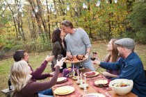 Couple kissing at outdoor dinner with friends — Stock Photo