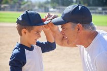 Ragazzo e nonno in berretti da baseball, faccia a faccia — Foto stock