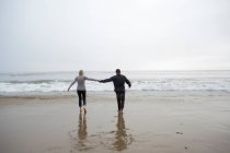 Couple d'âge mûr tenant la main sur la plage — Photo de stock