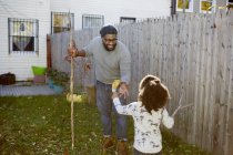 Девушка подает осенний лист своему отцу в саду — стоковое фото