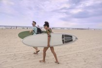 Young couple carrying surfboards on Rockaway Beach, New York State, USA — Stock Photo