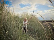 Мальчик играет с мечом на пшеничном поле — стоковое фото