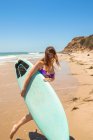 Молода жінка на пляжі з дошкою для серфінгу — стокове фото