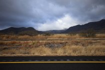 Rail tracks beside dry field and mountain range — Stock Photo