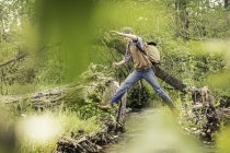 Ragazzo adolescente con zaino saltare attraverso il fiume — Foto stock