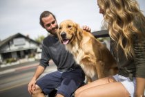 Young couple with dog sitting in back of jeep — Stock Photo